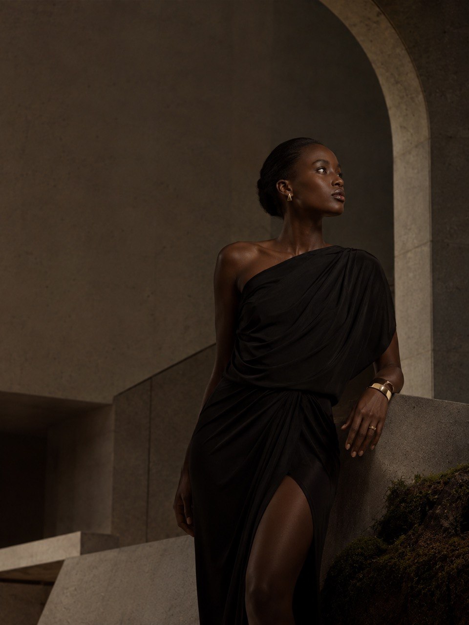 Model wearing Alnami jewelry beneath a monumental stone arch