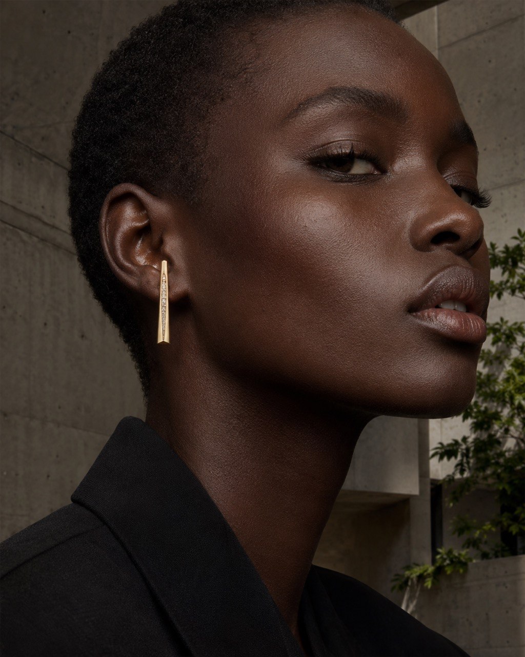 Close portrait of a model wearing a long architectural gold Alnami earring